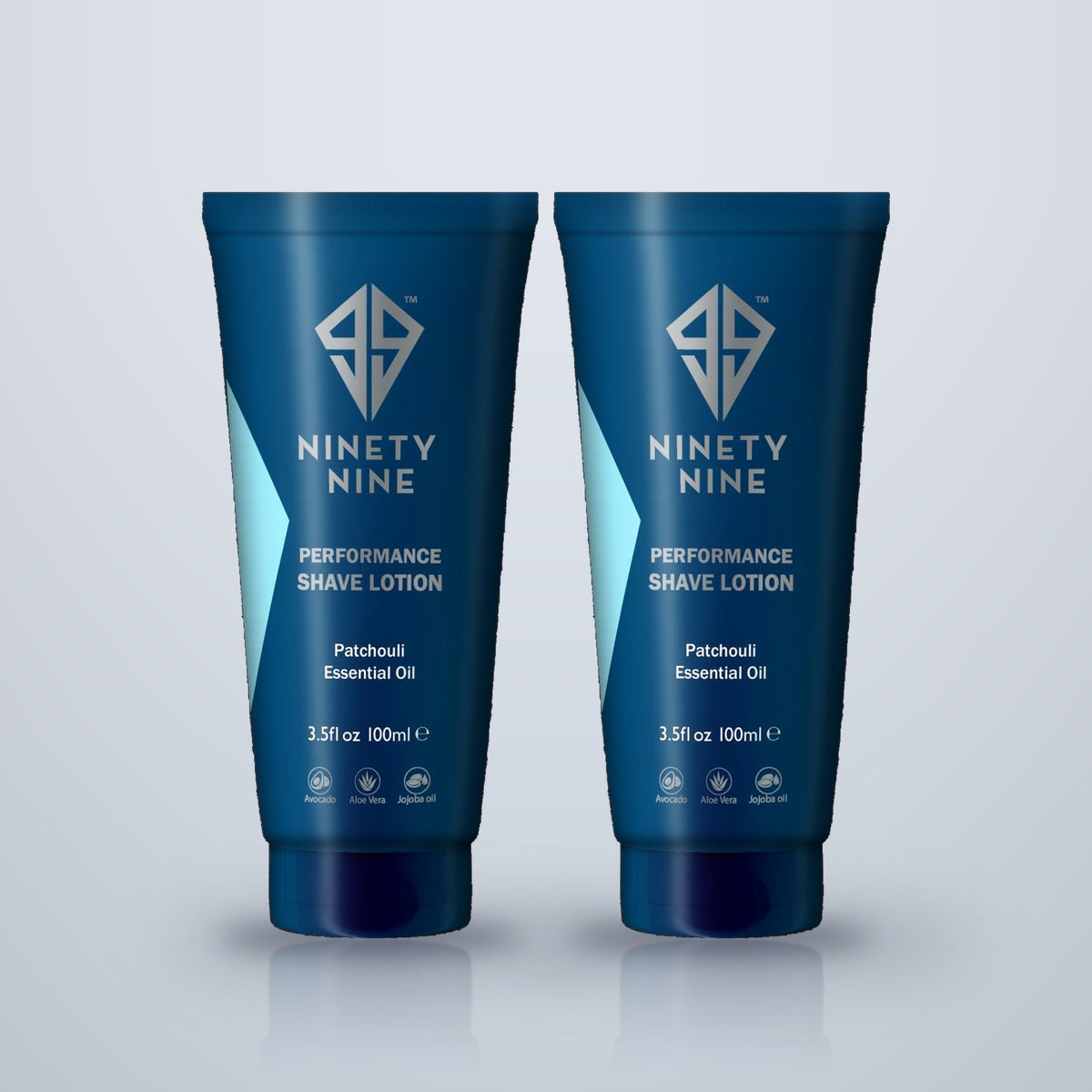 Two blue tubes of Ninety Nine Performance Shave Lotion with Patchouli Essential Oil, displayed side-by-side on a light gray reflective surface.