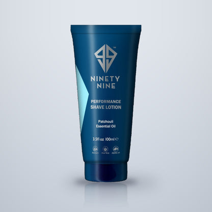 99 Performance Shave Lotion, 100ml tube. A dark blue squeeze tube of Ninety Nine Performance Shave Lotion with Patchouli and Essential Oil, shown on a light gray gradient background with a soft reflection.