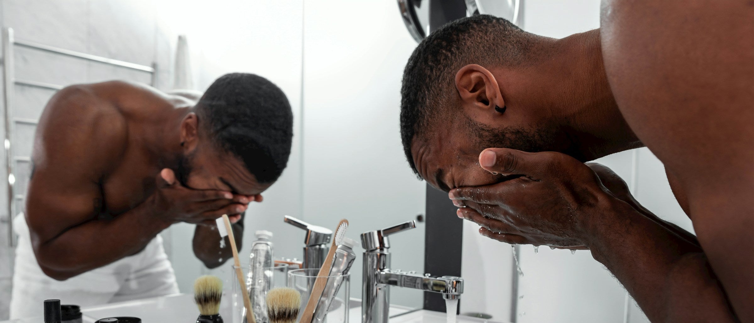 Man washing his face in a bathroom mirror.